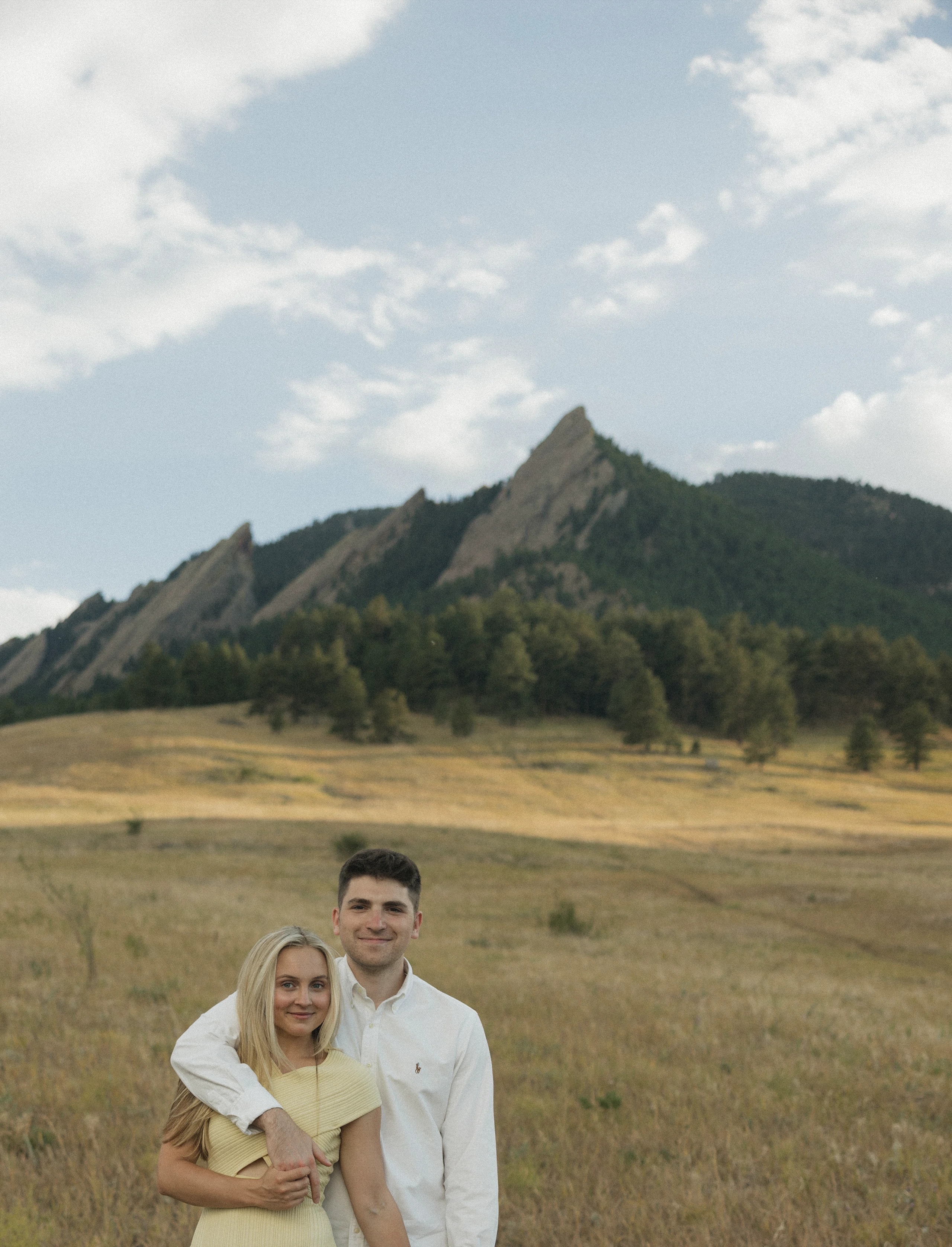 Anna and Emmett standing in a golden field below the Flatirons in Boulder
